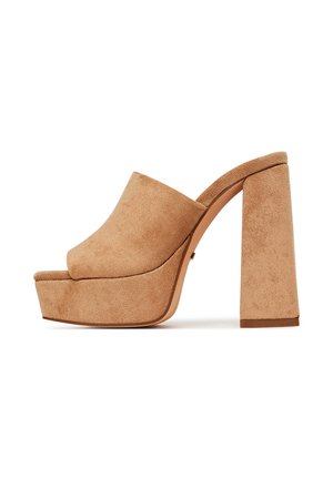 Zamszowe beżowe klapki na platformie z szerokim, otwartym noskiem i masywnym, kwadratowym obcasem. Gładka faktura i profilowany kształt zapewniają stabilność.