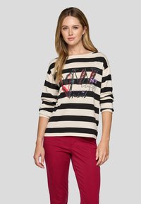 Gestreiftes Langarmoberteil in Creme und Schwarz, mit einem grafischen Design, das Text und Herzen in Rot und Lila zeigt. Weiches Strickmaterial.