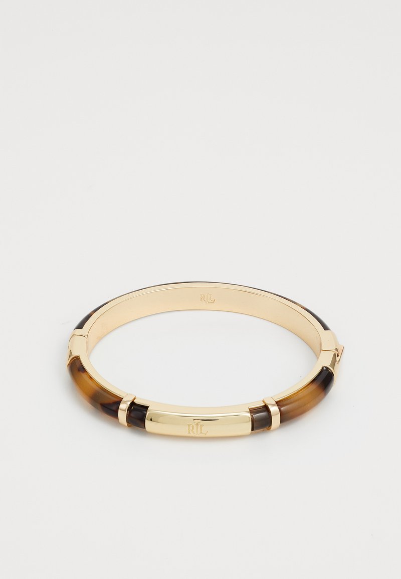 Gulltonet metallarmbånd med veksling mellom brune og svarte harpikseksjoner. Glatt tekstur med gravert logo på den sentrale metalldelen.