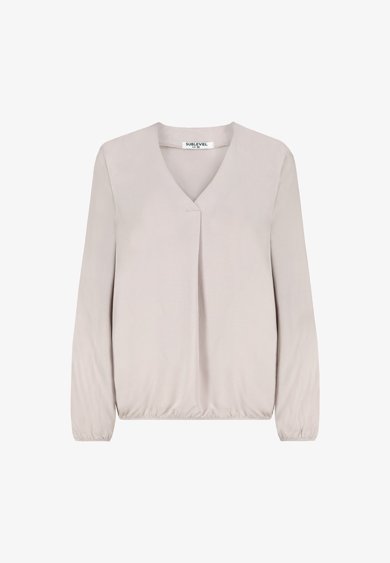 Light beige long-sleeve blouse with V-neck, subtle front pleat, elastic cuffs, and elastic hem, size medium, displayed on white background.