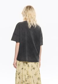 Tumehall oversized t-särk, lühikeste varrukatega, pehme tekstuuriga. Kombineeritud mustrilise kollase seelikuga, millel on lillemotivid.