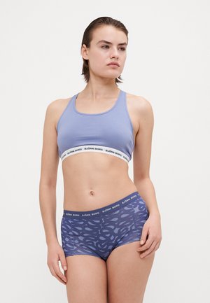 Soutien-gorge de sport violet clair avec une ceinture blanche contrastante sur laquelle est inscrit "BJÖRN BORG" ; short garçon noir avec un motif abstrait assorti.
