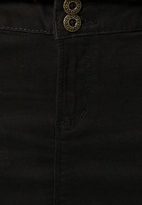 Mustat farkkuhame, jossa on kaksi koristeellista kultanappia vyötäröllä. Hameessa on kevyitä ompelus yksityiskohtia ja sileä, teksturoitu pinta.