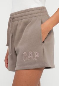 Gray cotton blend shorts with an elastic waistband, side pockets, and embroidered "GAP" logo on the front. Smooth texture, above knee length.