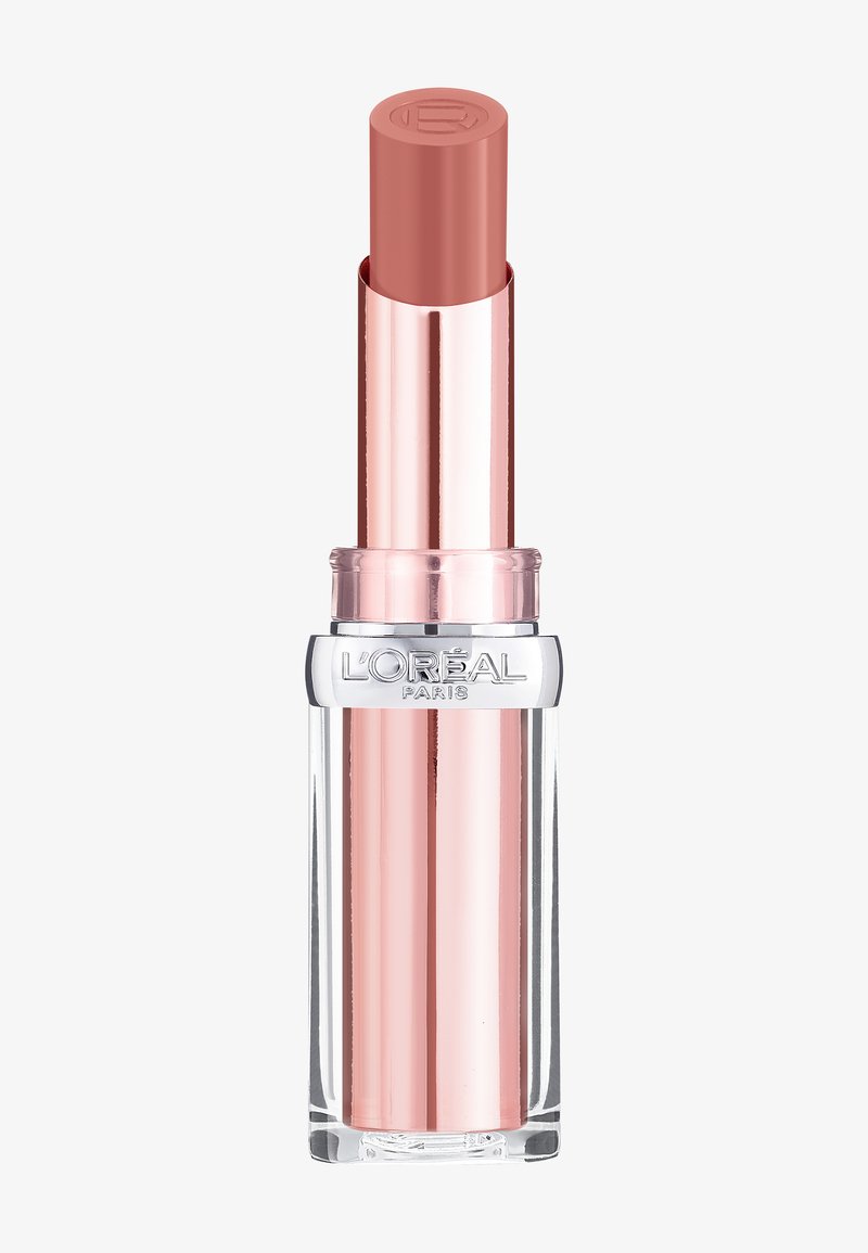 Läppstiftstube med en genomskinlig bas. Det yttre höljet är metalliskt rosguld, och själva läppstiftet är en mjuk nude-rosa. Har varumärkets logotyp på toppen.