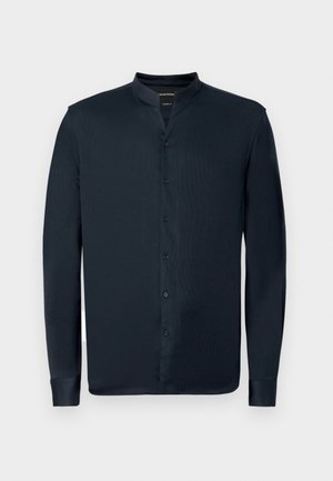 Srajca s dolgimi rokavi, temno mornarska barva, z ovratnikom in sprednjim zapenjanjem na gumbe. Ima gladko teksturo in temne gumbe.