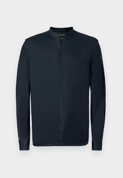 Srajca s dolgimi rokavi, temno mornarska barva, z ovratnikom in sprednjim zapenjanjem na gumbe. Ima gladko teksturo in temne gumbe.