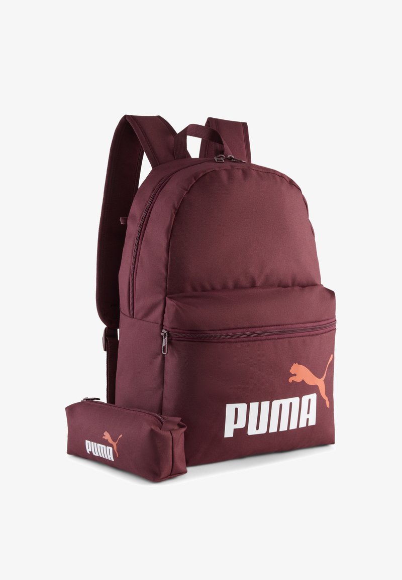 Bordeaux kleurige stoffen rugzak met een afgeronde vorm, voorzien van een voorvak, ritssluiting en een wit Puma-logo met een oranje accent.