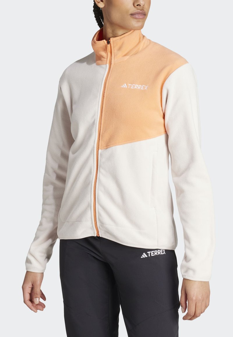 Chaqueta de forro polar con un cuerpo blanco y un panel superior naranja, cuello alto, cremallera frontal y bolsillos laterales. Logotipo en el lado izquierdo del pecho.