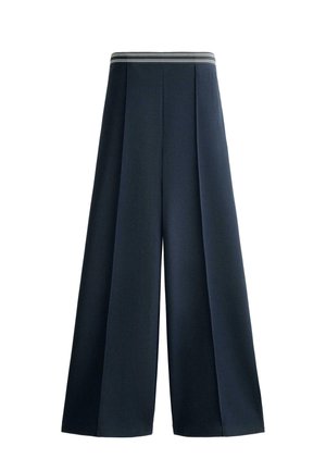 Pantalon large bleu marine avec une taille haute élastique présentant des rayures blanches horizontales, des plis devant, et une coupe ample.