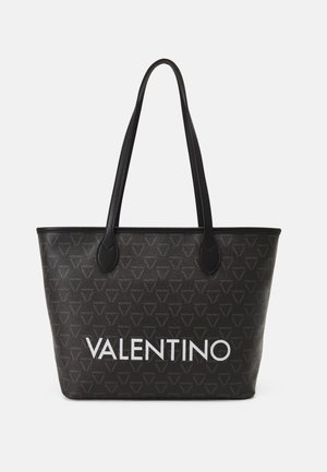 Black tote bag with textured fabric, featuring a repeating triangular pattern. A prominent white “VALENTINO” logo printed on the front.