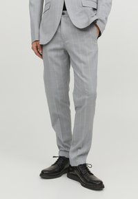 Harmaat ruutukuosiset pukuhaalari, joka on valmistettu sileästä kankaasta, slim fit -leikkauksella, litteällä edessä ja taskuissa yksityiskohtia. Yhdistetty mustiin nahkakenkiin.