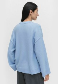 Jasnoniebieski, oversize sweter z ribbanym wykończeniem rękawów i dołu, wykonany z miękkiego materiału, z klasycznym okrągłym dekoltem i luźnym krojem.