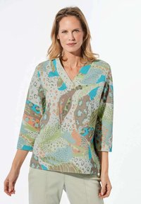 V-hals tuniek top met een kleurrijk abstract patroon in groene, blauwe, oranje en bruine tinten. Gemaakt van textuurstof, met driekwart mouwen.