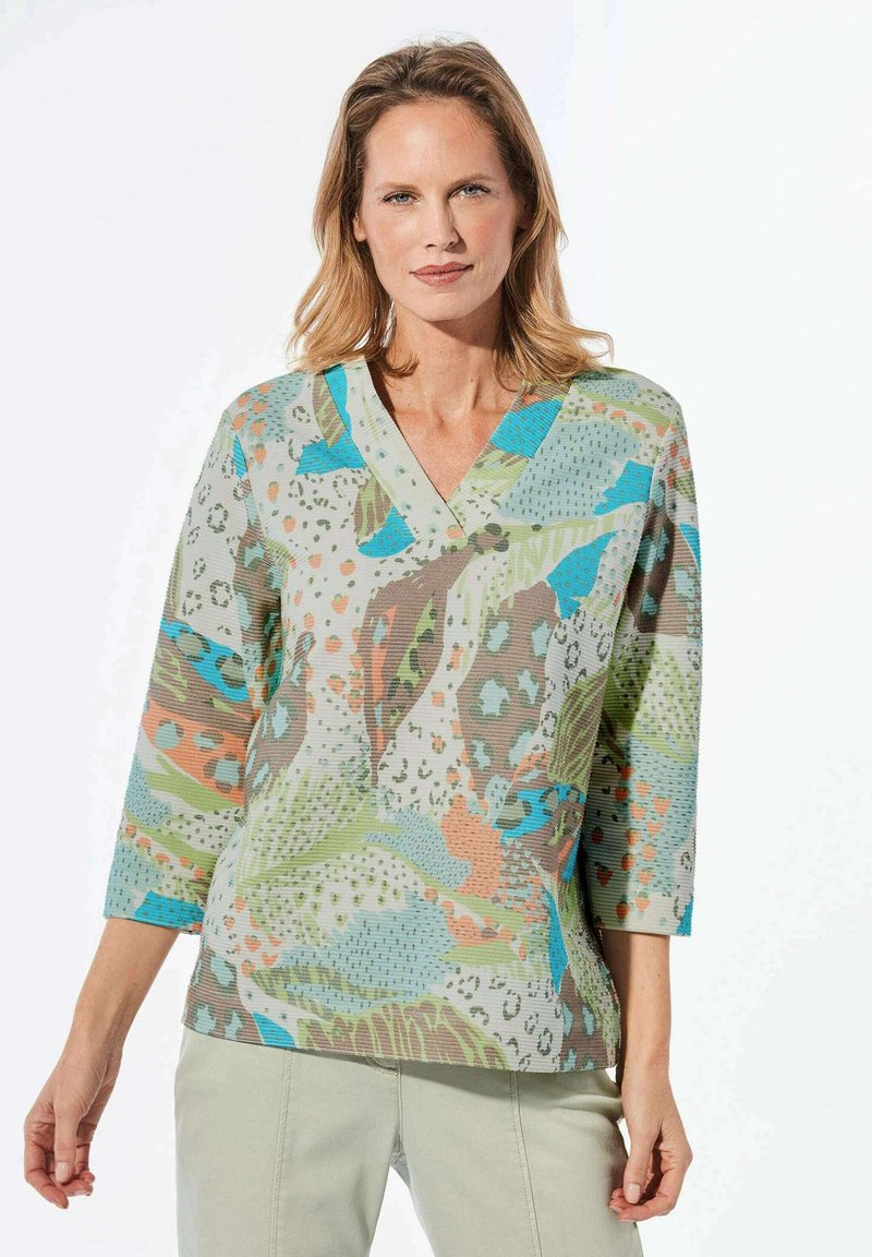 V-hals tuniek top met een kleurrijk abstract patroon in groene, blauwe, oranje en bruine tinten. Gemaakt van textuurstof, met driekwart mouwen.