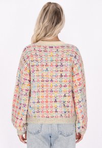 Maglione oversize colorato a maglia con un motivo tessuto testurizzato in tonalità pastello. Polsini e orlo a costine beige. La vista posteriore mostra una vestibilità morbida e rilassata.