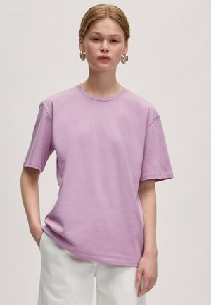 T-shirt à col rond lavande avec des manches courtes, fabriqué dans un tissu doux. Présente une coupe décontractée et des détails de couture minimes.