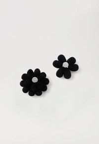 Due accessori neri a forma di fiore realizzati in materiale morbido, con design dei petali arrotondati e hardware argento al centro.