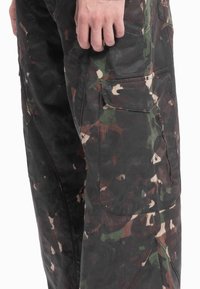 Cargo-bukser i kamuflasjemønster med mørkegrønn, brun og kremfarge. Robust stoff med lommepatcher og glidelåsdetaljer.