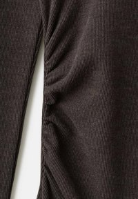 Donkerbruin geribd stof met geraffineerde details langs de naad, met een subtiele textuur en een zachte, rekbare uitstraling.