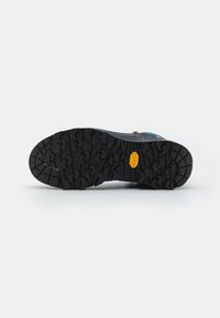 Svart gummisåle med dype spor, med Vibram-logoen. Sålen er formet for grep og holdbarhet.