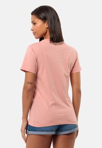 Korte roze T-shirt met korte mouwen, ronde halslijn en een relaxte pasvorm, gecombineerd met denim shorts. Zachte textuur en minimale detailering.