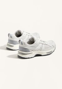 Lätta löparskor med ovandel i mesh i vitt och grå accenter, med en dämpad sula och texturerat gummimönster för bättre grepp.