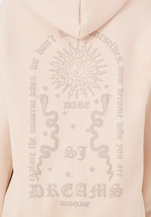 Hoodie rosa chiaro con una grande grafica testurizzata sulla schiena che presenta un sole, simbolo del yin-yang, serpenti e testo stilizzato.