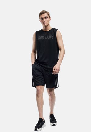 Sort ærmeløs træningsskjorte med "RUN CLUB" tekst, parret med sorte shorts med hvide sidestriber og sorte løbesko.