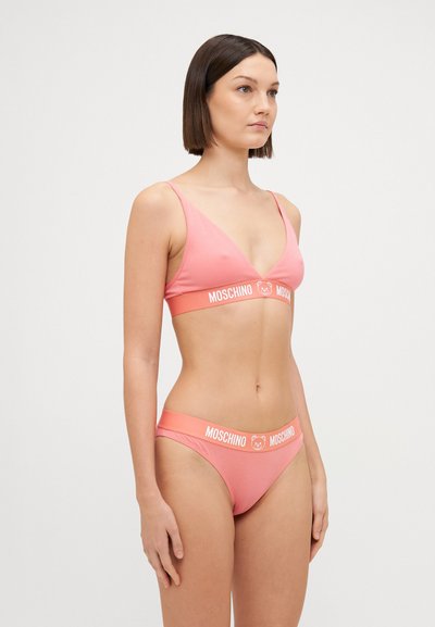 Rozā bikini komplekts, kas sastāv no triangelveida krūštura un zemu jostasvietu biksītēm. Abas daļas rotā plata apelsīnu krāsas logo josla. Gluda, elastīga materiāla.