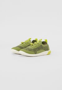 Lettvekt grønne sneakers med teksturert strikket overdel, elastiske snørebånd og kontrastfarget kremfarget såle. Har trekksløyfer for enkel påkledning.