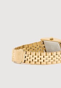 Χρυσό μεταλλικό ρολόι με εξαγωνική πρόσωπο και αλυσίδα με κούμπωμα. Το ρολόι διαθέτει γυαλιστερή επιφάνεια και διαφανές κάλυμμα.