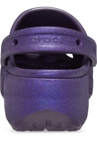 Lila Glitzer Crocs mit geschlossener Zehenpartie, Fersenriemen, strukturiertem Außenmaterial und offenen Belüftungsöffnungen für Atmungsaktivität.