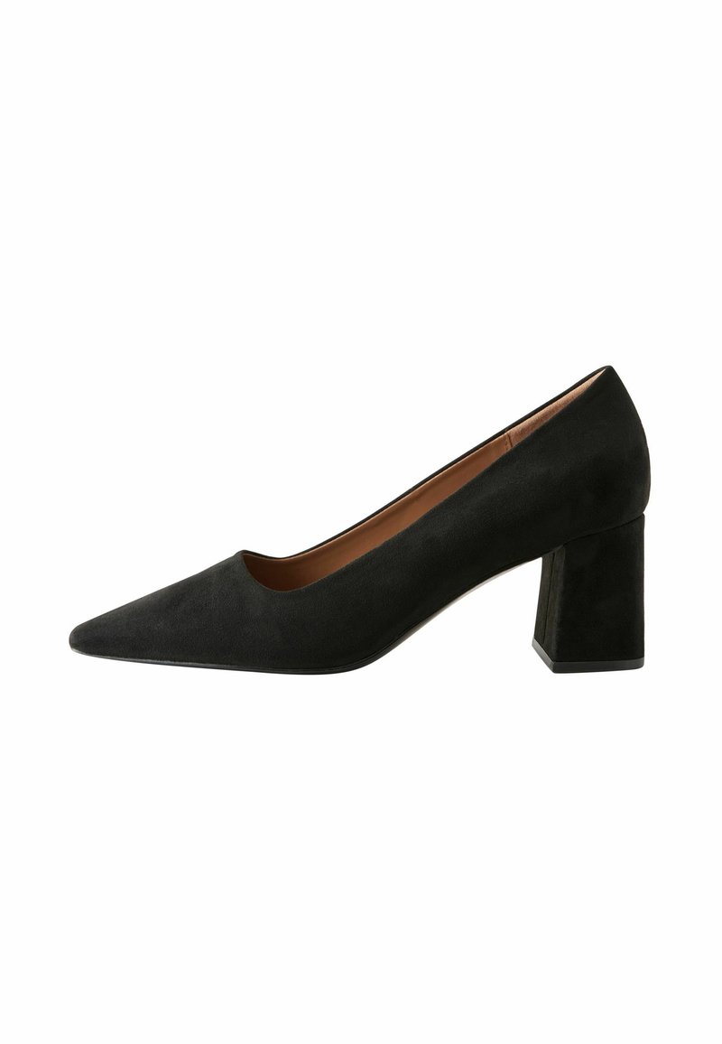 Zapato de tacón alto de ante negro con punta afilada, textura suave y tacón rectangular grueso. Interior en un color marrón contrastante.