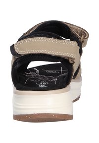 Sandali sportivi beige con cinturini neri accentati, chiusure in velcro regolabili, suole imbottite e una soletta texturizzata con design grafico.