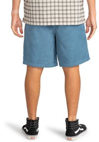 Pantaloni corti in corduroy blu con una vestibilità dritta, caratterizzati da una superficie testurizzata e un orlo all'altezza del ginocchio, abbinati a scarpe da ginnastica nere alte.