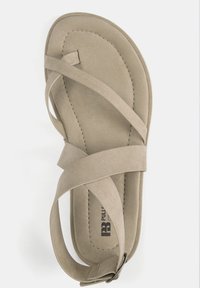 Beige suede sandaal met een kruisbandontwerp, open teen en een platte zool. Voorzien van een zijgesp en gestikte details.