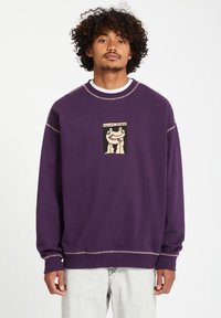 Paarse sweatshirt met een witte kraag, voorzien van een grafische print aan de voorkant in tan en zwart. Inclusief contrasterende stiksels langs de naden en manchetten.