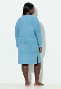 Nebesky modré šaty s dlouhým rukávem, diamantovým vzorem, kulatým výstřihem a bočním rozparkem, vyrobené z měkké látky.