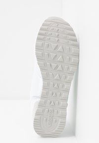 Semelle blanche de sneaker avec motif de bande de roulement géométrique et logo "Skechers" embossé près du talon sur un fond blanc uni.