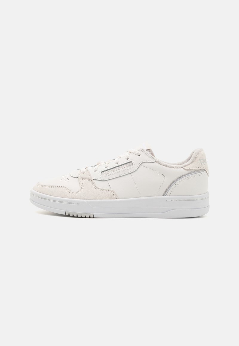 Baskets basses blanches avec lacets, marquage Reebok sur le côté et semelle blanche épaisse sur fond uni.