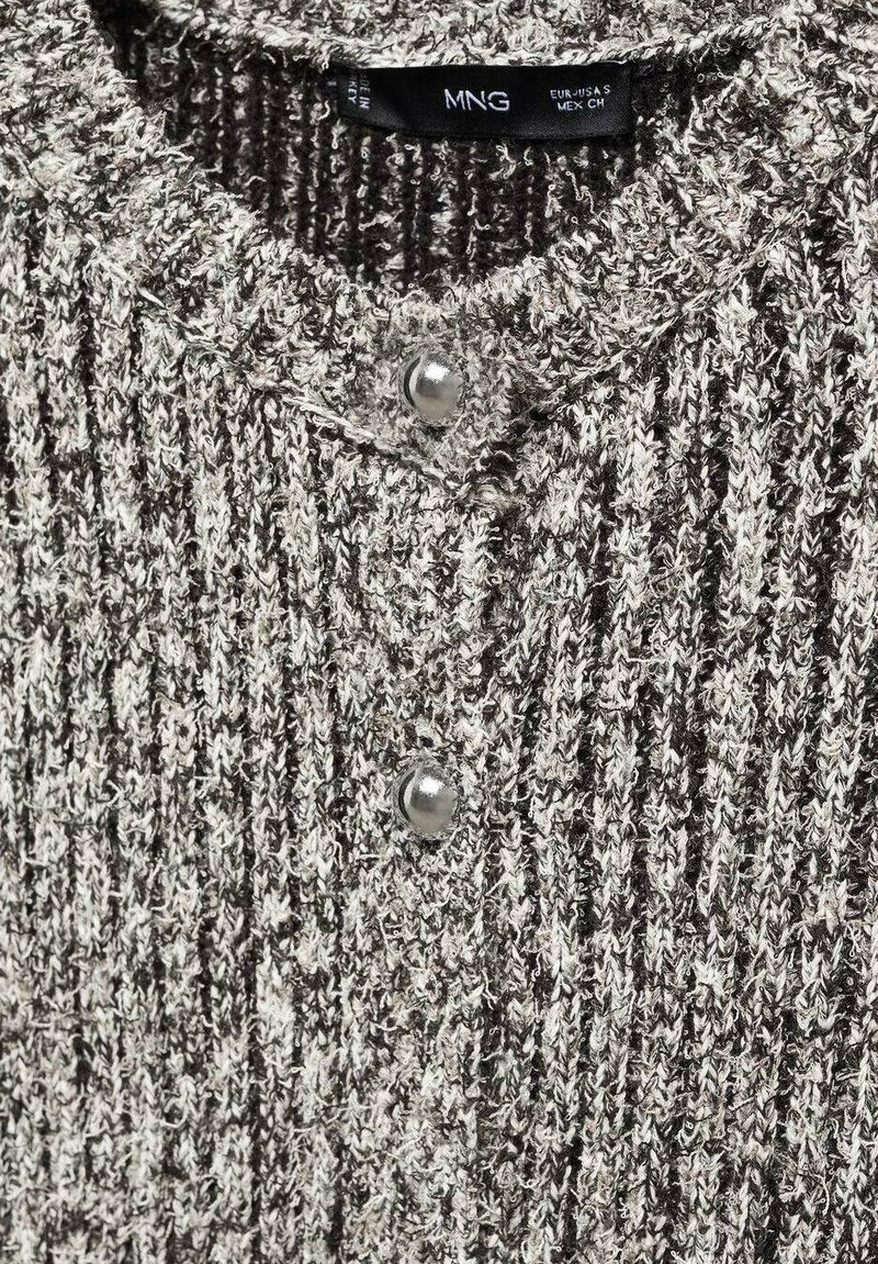 Pull en maille aux tons gris et crème, présentant une texture côtelée, un col rond et deux boutons-pression argentés au niveau du col.