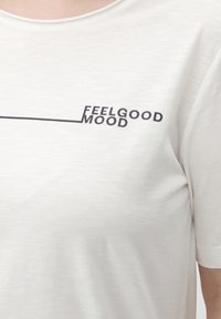 Svijetloplavi kratki rukav T-shirt s teksturiranom tkaninom koja sadrži crni otisnuti slogan "FEELGOOD MOOD" u modernom fontu.