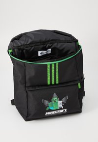 Zaino black con accenti verdi, personaggi pixelati di Minecraft e tre strisce verticali verdi sul fronte. Scomparti con cerniera visibili.