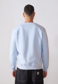 Ljusblå sweatshirt med rund hals och långa ärmar, med ribbade muddarna och nederkant, tillverkad av mjukt, texturerat tyg.