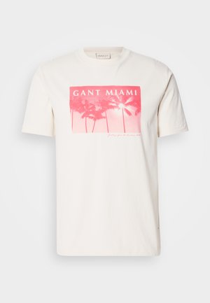 T-shirt de algodão branca com uma impressão gráfica em rosa com palmeiras e texto "GANT MIAMI". Manga curta e design de gola redonda.