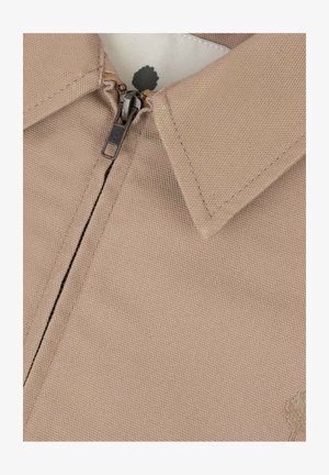 Beige stoffen jas met een ritssluiting die half dicht is, waarbij de kraag en het bovenste deel van de borst zichtbaar zijn.