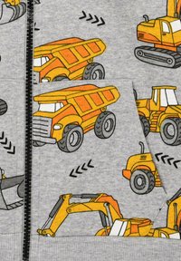 Gray sweatshirt featuring various yellow construction vehicle prints, including dump trucks and excavators, with a textured fabric and zip closure.