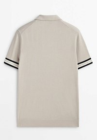 Polo à manches courtes beige avec un col, présentant des accents rayés noirs et blancs sur les manches. Texture lisse et design simple.