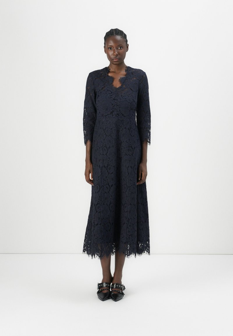 Navy blue lace dress with a scalloped neckline and three-quarter sleeves; features a knee-length, flared skirt and intricate floral patterns.